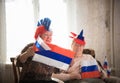 Pastimes. An elderly women supports sport team with flags sitting against TV on the backgrond of shining window