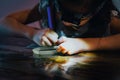 Pasting gemstones, a little girl is making artwork with her own hands