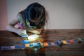 Pasting gemstones, a little girl is making artwork with her own hands at home.