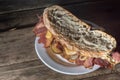 Pastrami sandwhich on a wooden tablet with delicious meet on baguette bread with cheese,copy space in parts of the image