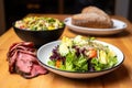 pastrami sandwich on rye beside a bowl of mixed salad Royalty Free Stock Photo