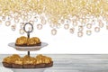 Pastries, desserts and sweets. Chocolate candies wrapped in golden foil on a two-storey etagere on a wooden table. Abstract bright Royalty Free Stock Photo