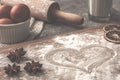 Pastry board with heart flour on the concrete countertop with eggs in the white bowl