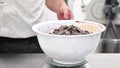 Pastry Chef adding chocolate pieces ready to melt. Ingredientes of the recipe of a chocolate cake.