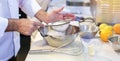 Pastry chef Baker sieving flour into a bowl in the kitchen of the bakery