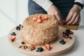 The pastry chef decorates the cake with berries. Delicious honey cake with berries. Home confectionery factory. Close-up of a Royalty Free Stock Photo