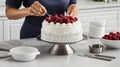 Pastry chef decorating cake with raspberries and whipped cream