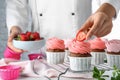 Pastry chef decorating delicious cupcakes with fresh strawberries at table, closeup Royalty Free Stock Photo