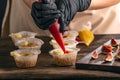 Pastry chef fills muffins with jam. Process of making cupcake by hand. Woman is cooking pastries Royalty Free Stock Photo