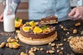 Pastry chef in hand holding a piece of chocolate cake with orange, mint and nuts. Healthy raw desserts for vegan food Royalty Free Stock Photo