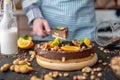 Pastry chef in hand holding a piece of chocolate cake with orange, mint and nuts. Healthy raw desserts for vegan food Royalty Free Stock Photo