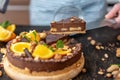 Pastry chef in hand holding a piece of chocolate cake with orange, mint and nuts. Healthy raw desserts for vegan food Royalty Free Stock Photo