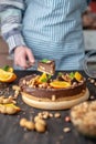 Pastry chef in hand holding a piece of chocolate cake with orange, mint and nuts. Healthy raw desserts for vegan food Royalty Free Stock Photo