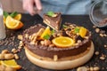 Pastry chef in hand holding a piece of chocolate cake with orange, mint and nuts. Healthy raw desserts for vegan food Royalty Free Stock Photo