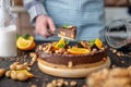 Pastry chef in hand holding a piece of chocolate cake with orange, mint and nuts. Healthy raw desserts for vegan food Royalty Free Stock Photo