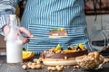 Pastry chef in hand holding a piece of chocolate cake with orange and peanuts. Healthy raw desserts for vegan food Royalty Free Stock Photo