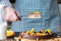 Pastry chef in hand holding a piece of chocolate cake with orange and peanuts. Healthy raw desserts for vegan food Royalty Free Stock Photo