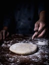 Pastry chef hand sprinkling white flour over Raw Dough on kitche