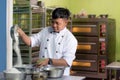 Asian male baker, pastry chef prepare dough with flour inside bakery kitchen