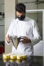 Pastry chef with mask working dosing desserts in glass