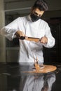 Pastry chef with mask working on tempering chocolate