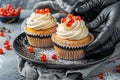 Pastry chef s hands in black gloves decorating cupcakes with cream cheese frosting and red berries