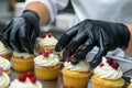 Pastry chef s hands expertly decorating cupcakes with cream cheese frosting and red berries