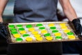 The pastry chef shows raw colored eclairs rings on a baking sheet