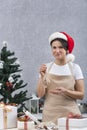 Pastry chef woman in a kitchen apron and New Years hat is packing delicious gifts. Vertical frame