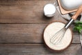 Pastry cream with balloon whisk on wooden table, flat lay. Space for text