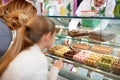 In pastry shop girl choose macarons from showcase