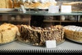 Pastry shop glass display with selection of cream or fruit cake, chocolate cake behind the glass of a showcase of a