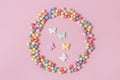 Pastry sprinkles are scattered in the form of a circle, inside it are enclosed colorful butterflies on a pink background Royalty Free Stock Photo