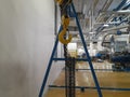 Pasuruan, 27 April 2022 : Industrial chain crane hooks hanging with sash in factory isolated against white wall background