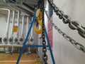 Pasuruan, 27 April 2022 : Industrial chain crane hooks hanging with sash in factory isolated against white wall background