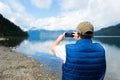 Patagonian Tranquility: Latin Middle-aged Man Enjoying Nature taking a photo with Mobile by Mountain Lake. Copy space