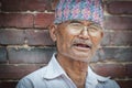 Unidentified Newari elderly man sit in front of the Mul Chowk Royal Palace in Patan Durbar Square - Nepal