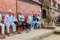 Patan, Nepal - September 21, 2016: Newari men and tourists resting on a bench by the Royal Palace, Durbar Square, Patan, Nepal