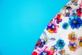 A patch of white fabric with multicolored flowers on a bright blue background. Space for text Royalty Free Stock Photo