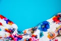 A patch of white fabric with multicolored flowers with drapery on a bright blue background. Space for text
