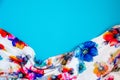 A patch of white fabric with multicolored flowers with drapery on a bright blue background. Space for text Royalty Free Stock Photo