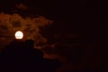 A Near Full Moon Piercing Through The Clouds