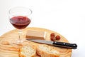 Pate, bread, glass of red wine, hazelnuts and knife on wood plat