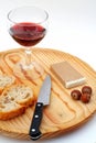 Pate, bread, glass of red wine, hazelnuts and knife on wood plat