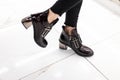 Patent black stylish fall boots with silver heel on female legs. Close-up of fashionable autumn-spring women shoes. New collection Royalty Free Stock Photo