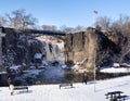 Wide horizontal view of tourists viewing the partially frozen falls at the historic Paterson