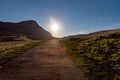 Path across the hills of Holyrood Park in Edinburgh, Scotland, with the sun rising bright at the end of the way. Popular Royalty Free Stock Photo