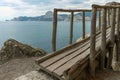 A path along the sea with a wooden bridge. The wooden bridge against the background of the blue sea and mountains Royalty Free Stock Photo