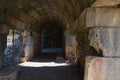 Path through a dark curved arched tunnel in old stone ruins