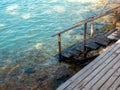 Path down to the sea. Empty wooden steps way on wood plank terrace on the beach, rocks and blue relax sea water. Royalty Free Stock Photo